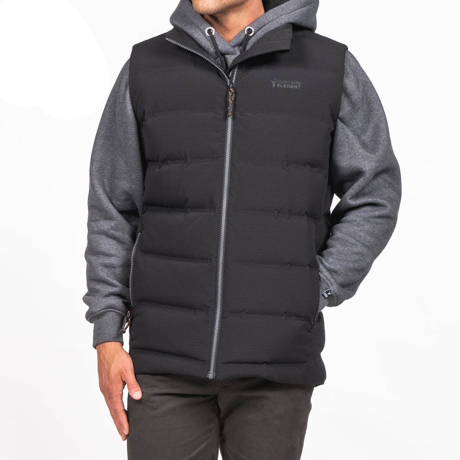 A person wearing a black down insulated vest with YKK zips, handwarmer pockets, and made from recycled plastic bottles fabric.